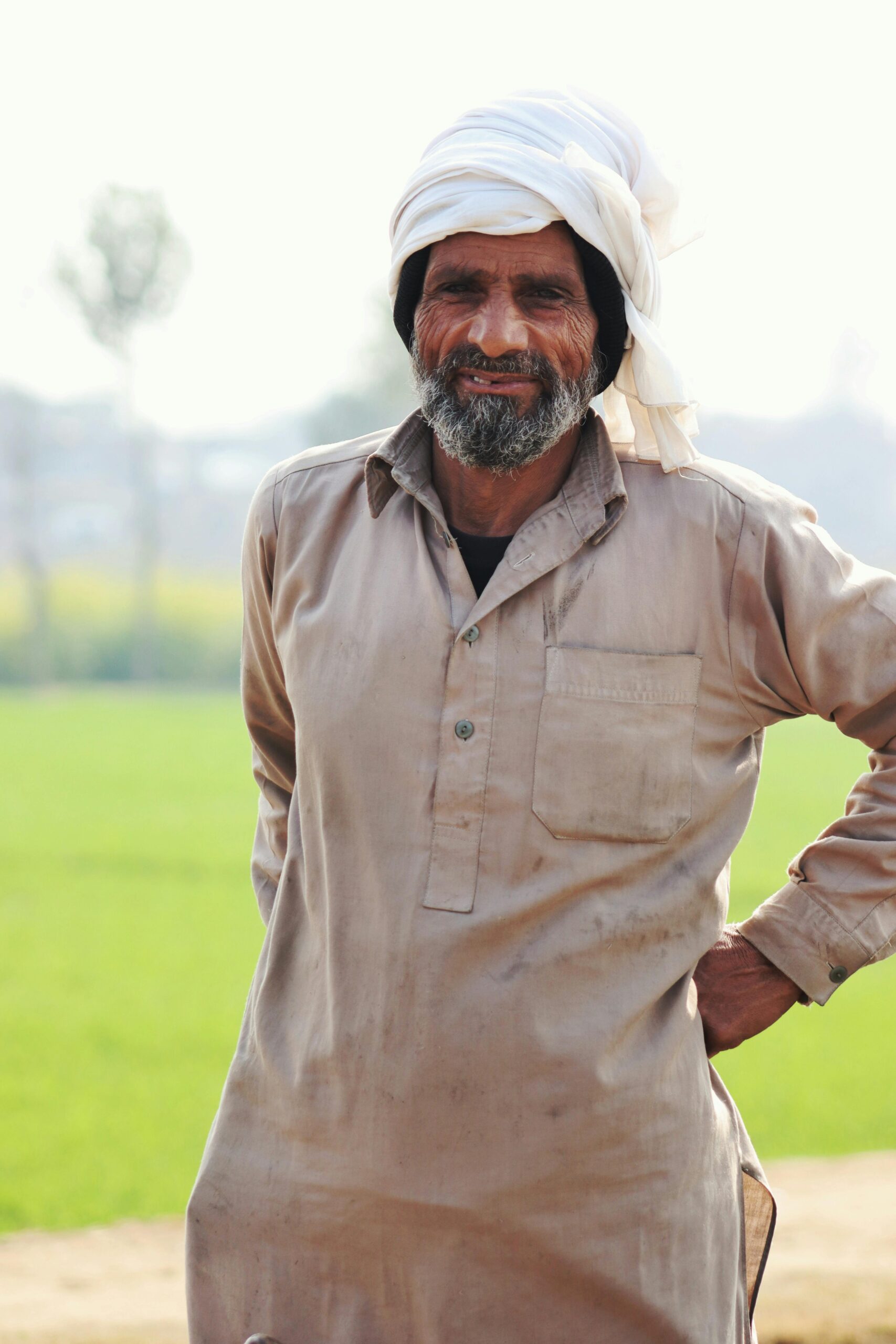 A South Asian farmer in traditional attire smiling in Lahore's vibrant fields.